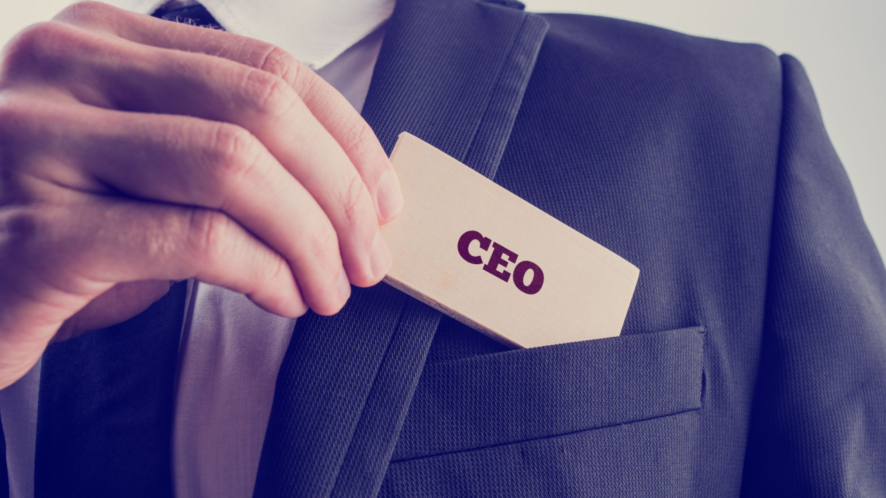 Close-up-of-a-hand-putting-a-CEO-badge-into-their-suit-pocket.jpg